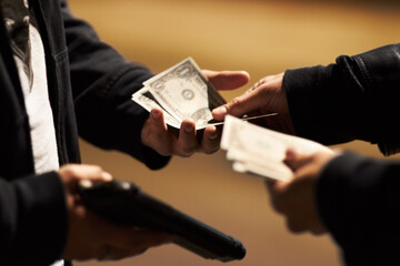 Sealing the deal. Hands holding cash and a gun passing money between them. - obrazy, fototapety, plakaty