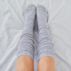 Socks are a must have for stay at home days. Cropped shot of a woman wearing grey socks in bed.