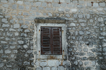 Fototapeta na wymiar the stone wall is old and the window with shutters
