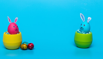 in two pots Easter eggs with hare ears stand on a blue background