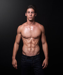 Fototapeta premium I make muscles not excuses. Studio shot of a handsome bare-chested young athlete standing against a black background.