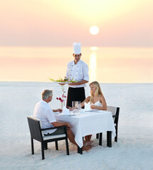 The perfect romantic dinner. Shot of a mature couple enjoying a romantic dinner on the beach.