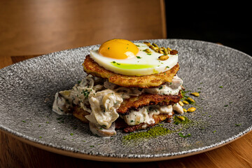 A close-up of potato pancakes with chicken meat, cream sauce and fried egg