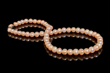 Pink pearl necklace on black background with reflection