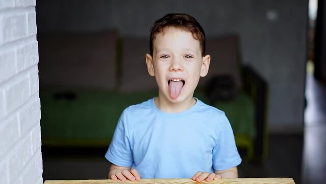 cheerful boy in blue t-shirt shows tongue