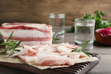 Tasty salt pork with rosemary on wooden board, closeup