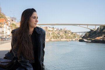 Fototapeta na wymiar Portait young woman in a city overlooking river and bridge .