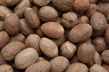 Heap of nutmeg seeds as background, top view