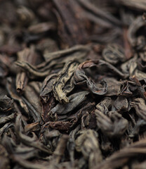 Dried black tea leaves as background.