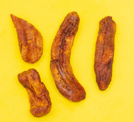 Dried bananas on a yellow background.
