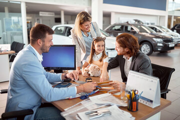 Family with  daughter buying a new car at the car showroom. - 490843634