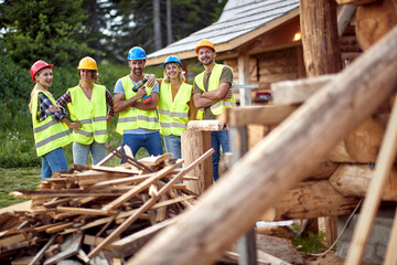 Group of construction workers powerful team. Young construction workers together, teamwork. Wooden Skeleton Framing Building. Construction industry, real estate, teamwork concept.