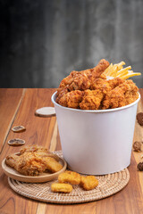 Fried chicken and french fries in paper bucket on wooden background, Deep fry Chicken and nuggets...