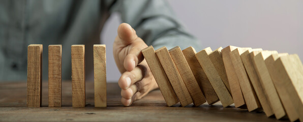 Hand prevent wooden block tower stack crash or fall domino. concept of prevention of financial...