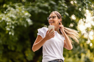 A young girl is dancing outdoors while listening to music on the phone. 