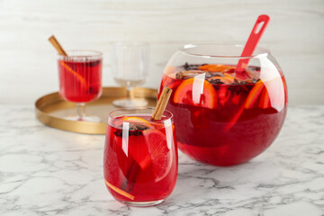 Glass and bowl of delicious aromatic punch drink on white marble table