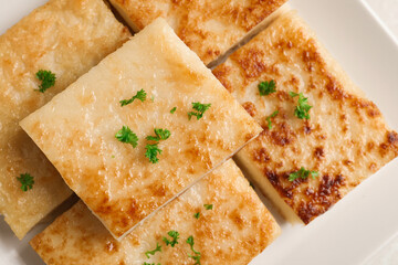 Delicious turnip cake with parsley on plate, top view