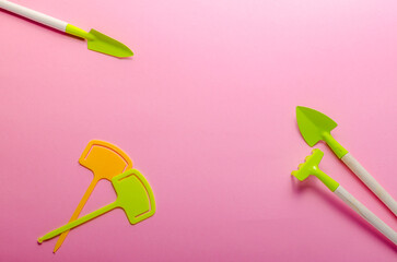 green garden tools on pink background