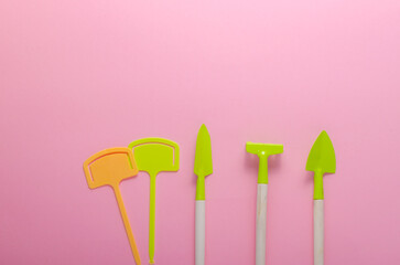 green garden tools on pink background