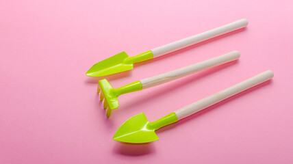 green garden tools on pink background