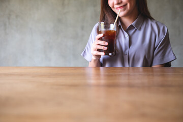 Closeup of a young asian woman holding and looking at a glass of iced coffee