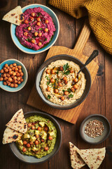 Various vegan hummus dips red beetroot green avocado and traditional chickpea.Traditional vegan hummus variety red beetroot green avocado and yellow chickpea with chia and sunflower seeds. Vegan diet 