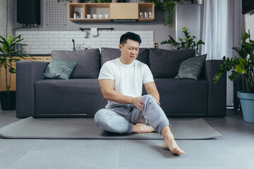 Asian Man in sportswear suffering from knee pain at home