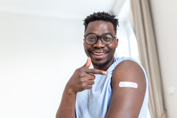 Portrait of a man smiling after getting a vaccine. African man holding down his shirt sleeve and...