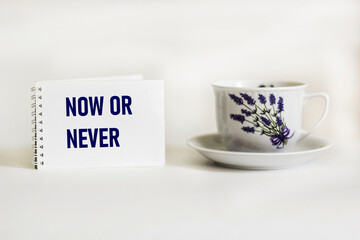 Inspirational quote Now or never on a notepad with a beautiful vintage mug and white background .Motivational typography.