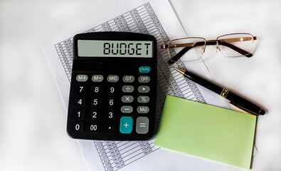 Budget concept. The text of the budget on the calculator lies on financial documents, next to it...