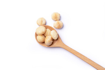 Macadamia nuts in wooden spoon isolated on white background. Top view. Flat lay.