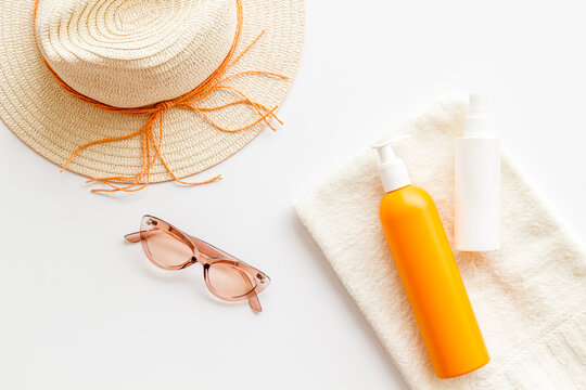 Straw hat and suntanning lotion on towel. Skin care with UV protection cosmetic
