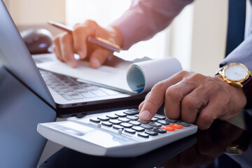 Businessman hand using calculator and signing financial check at office. Paycheck concept.