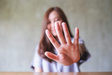 A young asian woman outstretched hand and showing stop hand sign