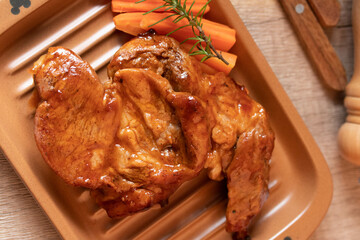 Meat during grilling. Chuck steak and rosemary garnished carrots.