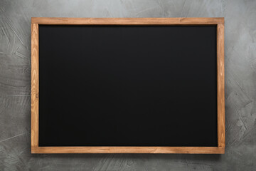 Clean black chalkboard with wooden frame on grey background