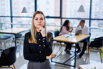 A young woman in a black shirt with bright emotions on her face, she stands against the background...