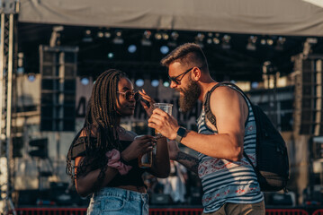 Romantic couple drinking beer and having fun at music festival