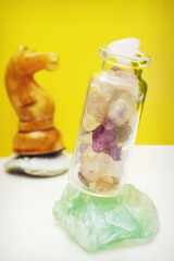 A chess piece is a knight in the background and a glass bottle with minerals in the foreground