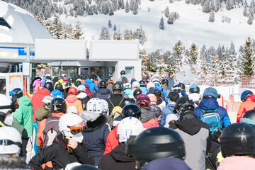 Long waiting line and crowded people in a skiing resort. Skiers and snowboarders queued up to get...