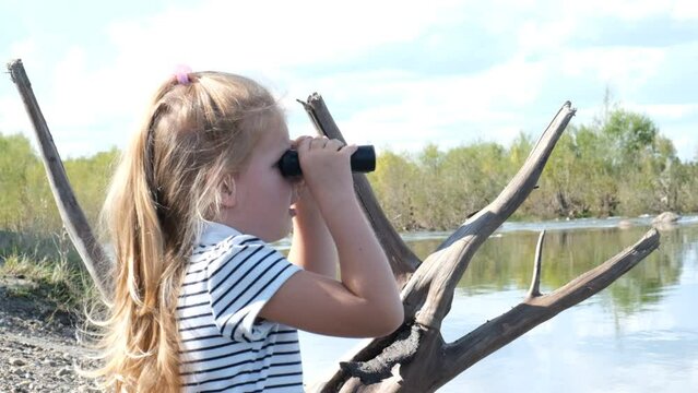 Little girl using binoculars in the forest. Exploring the world. Outdoor activities. Travel concept