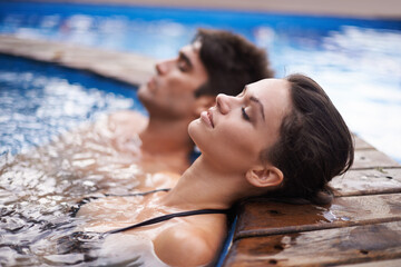 Letting their minds drift. Shot of an attractive young couple relaxing in a pool.