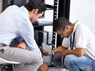 Finding the problem and correcting it. Two IT professionals working on a server.