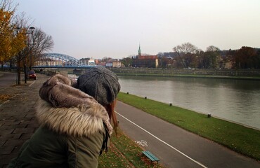 Mujer mirando el río Vístula y Most Marszalka Józefa Pitsudskiego (inglés: Marshal Jozef Pitsudskiego Bridge) en Cracovia, Polonia. - obrazy, fototapety, plakaty