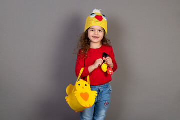 Little girl with a basket of eggs for the Easter holidays. Gray background for copying