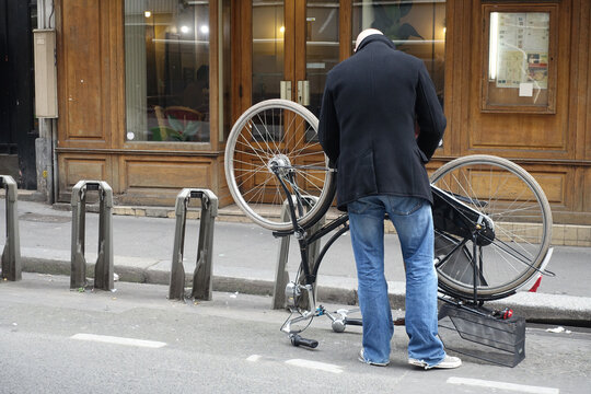Homme qui r&eacute;pare son v&eacute;lo en ville