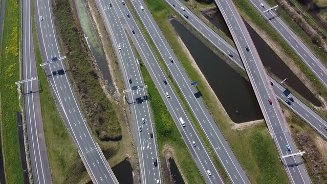 Aerial bird view footage of highway showing different bend roads moving past and over each other traffic driving both ways and sunshine reflection in water on side of motorwat 4k high resolution