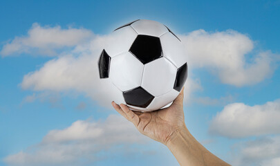 Close-up Of Soccer Ball On man hand with cloudy  and blue sky background for cheering image 