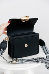 Fashionable women's small leather clutch bag with strap. Isolated on a white background. Traditional clutch bag with a brooch. Gold hardware. Close-up details of the bag. Bottom, handles, clasp. 