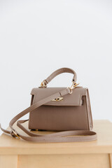 Fashionable women's small leather clutch bag with strap. Isolated on a white background. Traditional clutch bag with a brooch. Gold hardware. Close-up details of the bag. Bottom, handles, strap, clasp